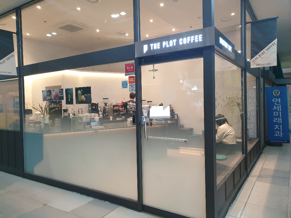 코너에 위치한 카페 유리와 검은색 프레임으로 구성된 카페