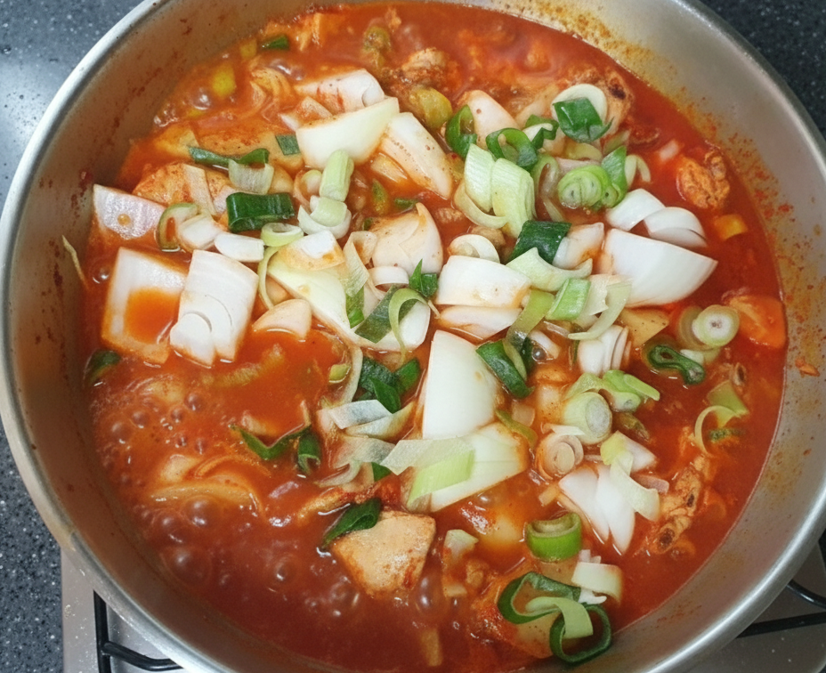 스틸 냄비에서 보글보글 끓고 있는 완성 직전의 맛있는 닭볶음탕과 신선한 대파 고명.