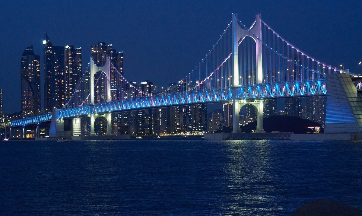 Gwangan Bridge lit in blue at dusk, seen from the Gwangalli Beach side in Busan