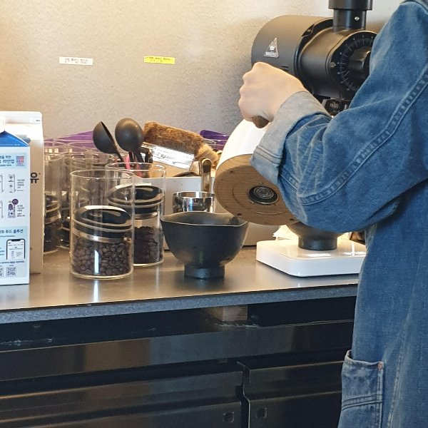 원두보관 통이 있고 그 앞에 다완 2개가 있다. 하나는 저울위에 올려져 있는데 그곳에 뜨거운 물을 붓고 있다.