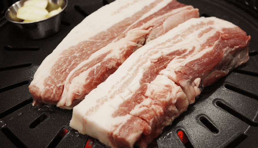 신장에 안 좋은 음식으로 삼겹살이 불판 위에 놓여 있다