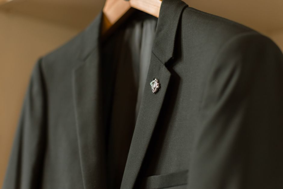 Close-up of a black suit with a badge on a hanger, showcasing fashion and style.