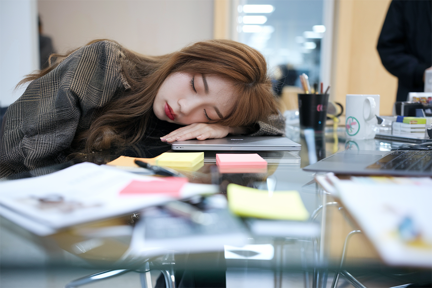 업무 중 책상에 엎드려 잠든 모습의 30대 직장인 여성의 모습으로, 수면 부족으로 인한 낮 시간 피로를 표현한 이미지