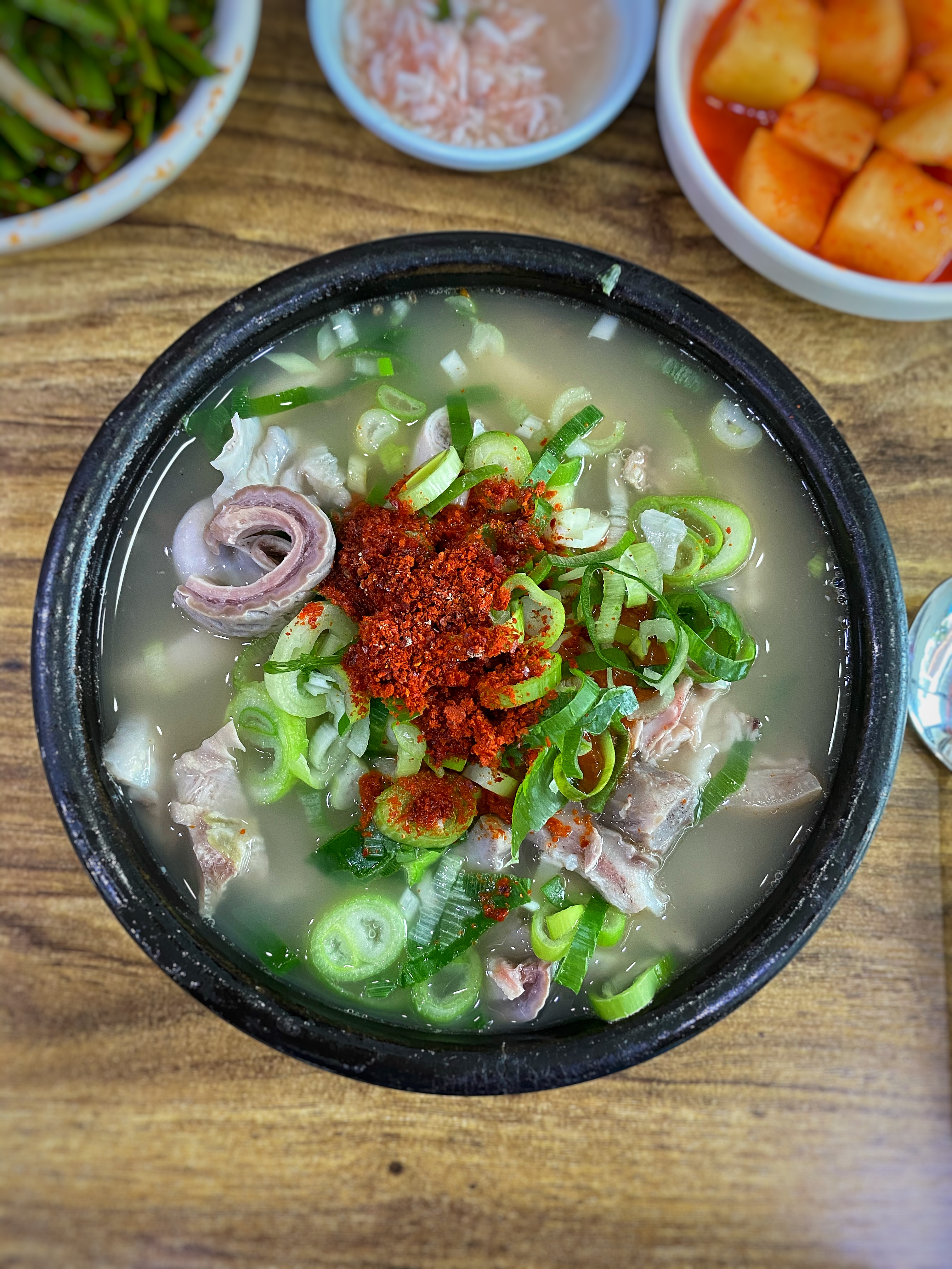 뚝배기에 담긴 돼지국밥. 먹기 좋은 온도감의 국물로 양념을 풀기 전에 국물을 먼저 맛보면 본연의 구수함을 느낄 수 있다.