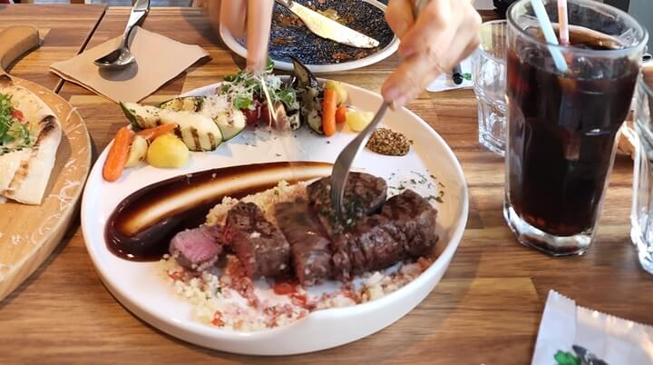 썰고 있는 안심스테이크와 잔에 든 콜라