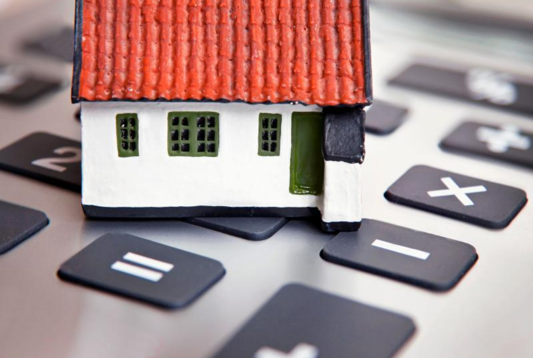 계산기 위해 놓여있는 주택 모형