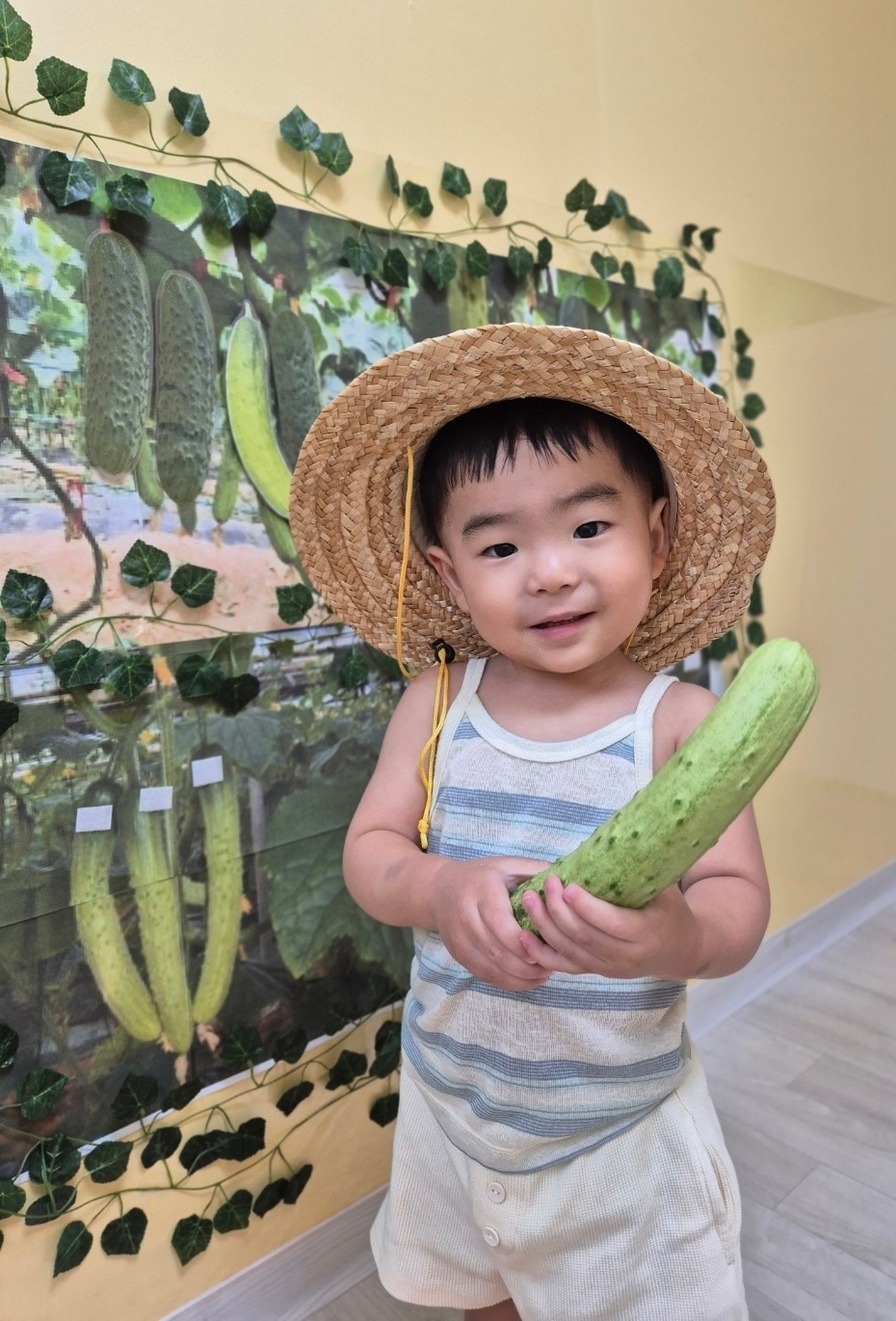 밀짚모자를 쓰고 오이를 수확한 아이