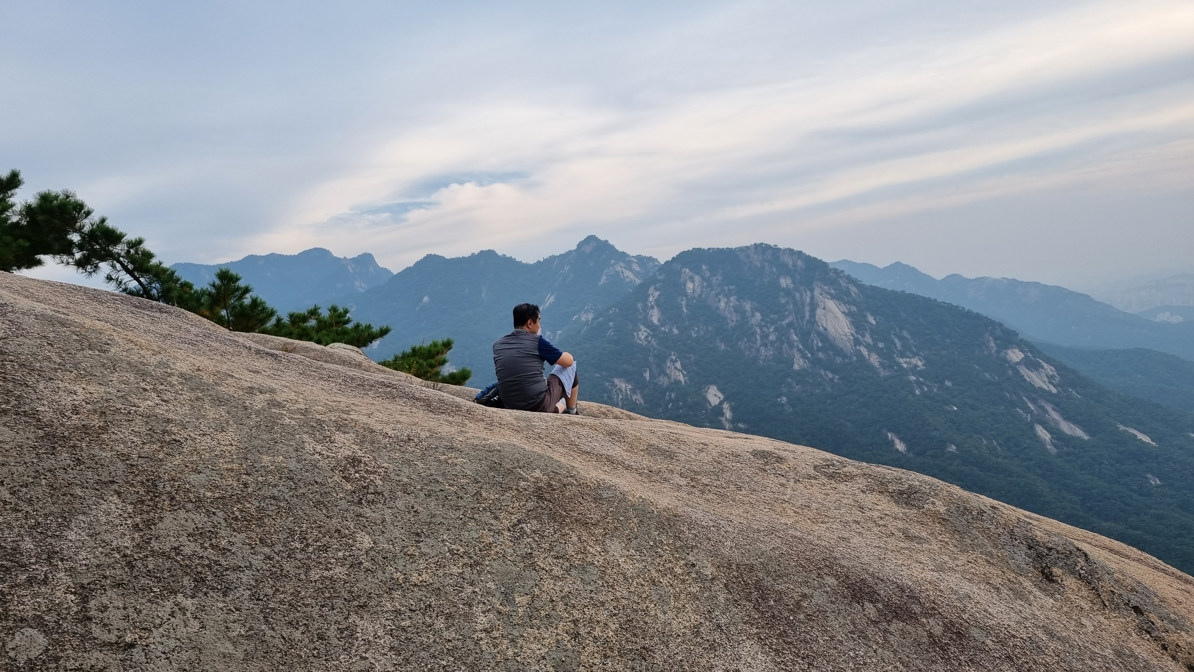 급경사 비탈 바위에 앉아 있는 등산객 남1