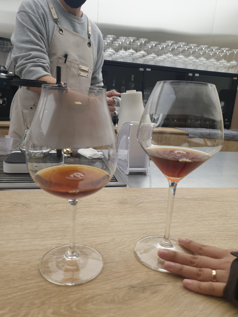 추출 후 정리 중인 바리스타와 두 개의 와인잔에 담긴 커피