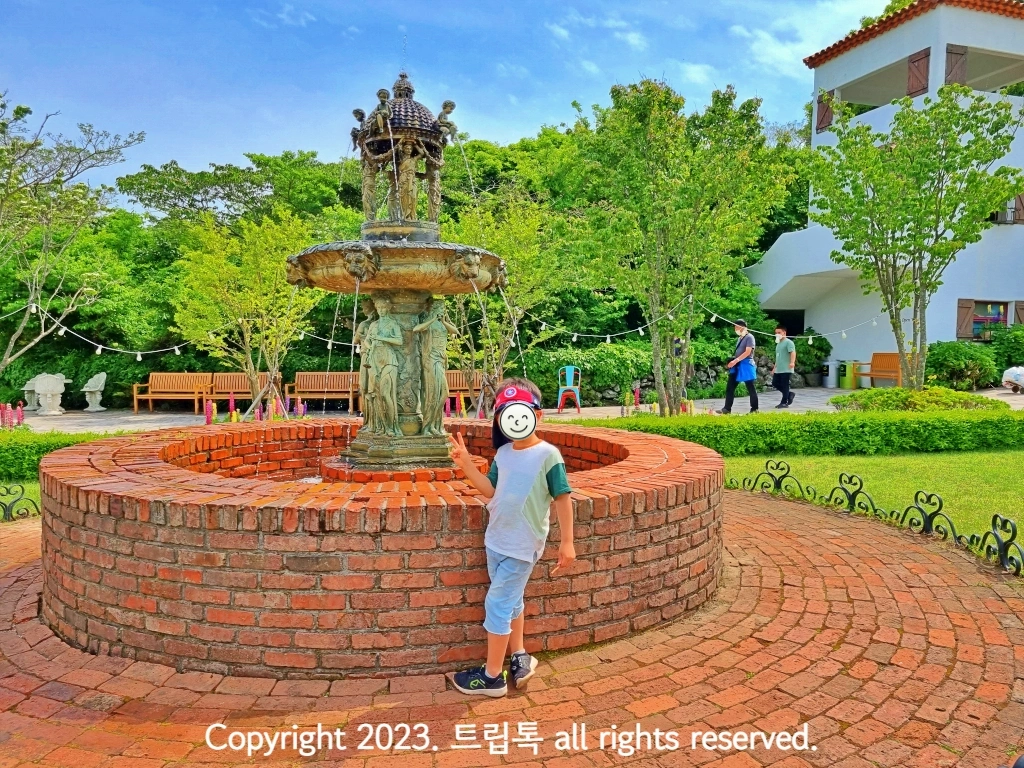 붉은 벽돌로 만든 분수대앞에서 사진찍는 아이
