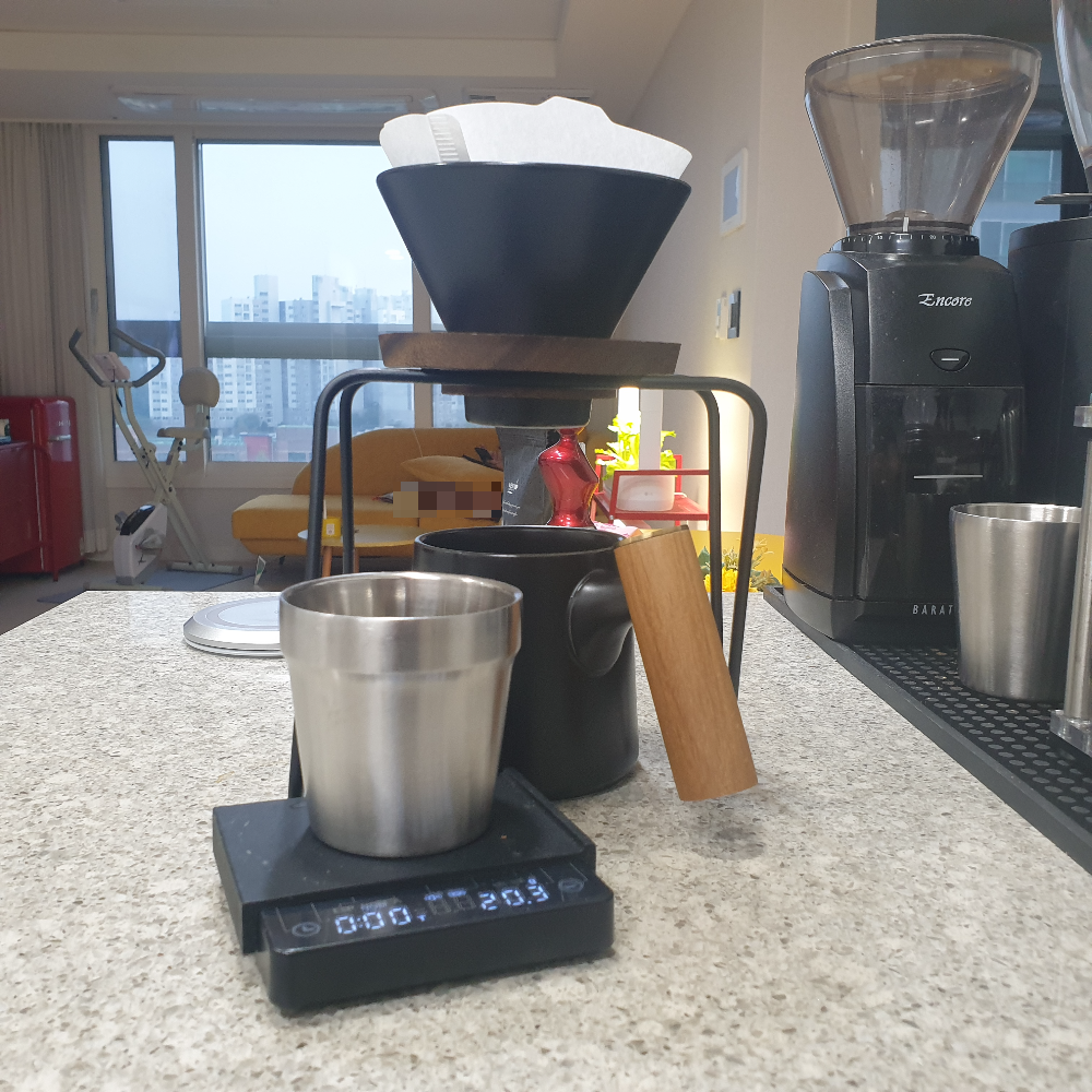식탁위에 드립 세트와 저울이 있다. 저울 위에는 원두 20.3g이 담겨 있다. 주변으로 그라인더도 보인다.