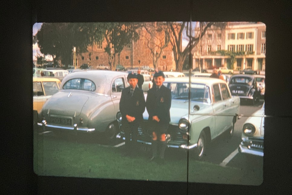 두 소년이 차 앞에서 사진을 찍기 위해 포즈를 잡고 있다.