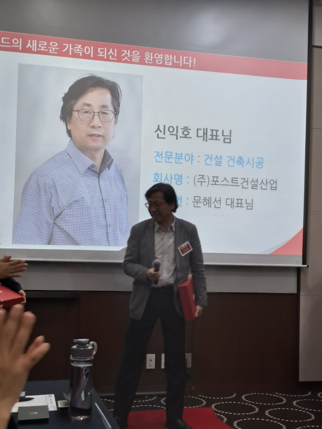 건축시공 포스트건설산업 신익호대표님께서 회의실 중앙에 서서 비엔아이 그랜드 챕터 멤버가입인사말을 발표하고 있습니다.