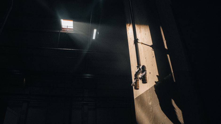 Dramatic lighting on industrial pipes casting shadows indoors, evoking a cinematic feel.