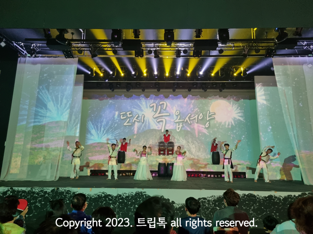 제주도 말로 다시 꼭 오라고 써있는 배경과 무대인사를 하는 배우들