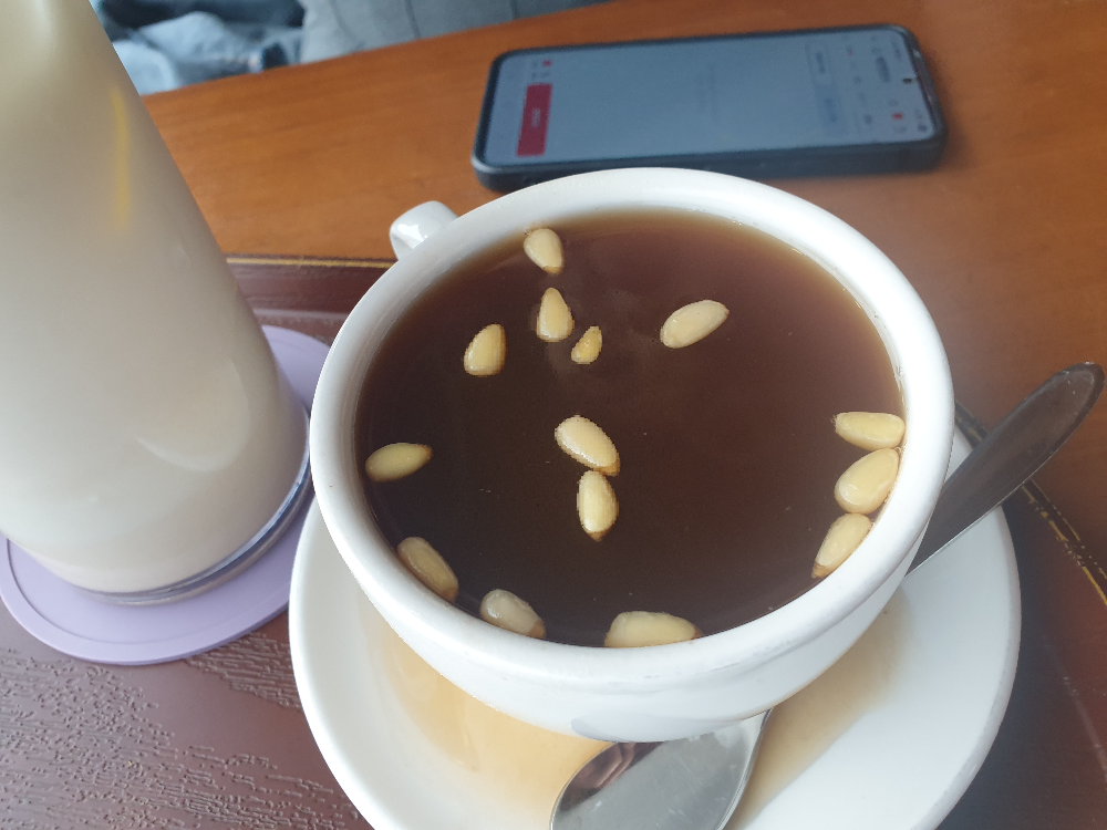 테이블 위에 잣이 둥둥 떠있는 계피 생강차. 너무 양이 많아 흘러 넘친 모습