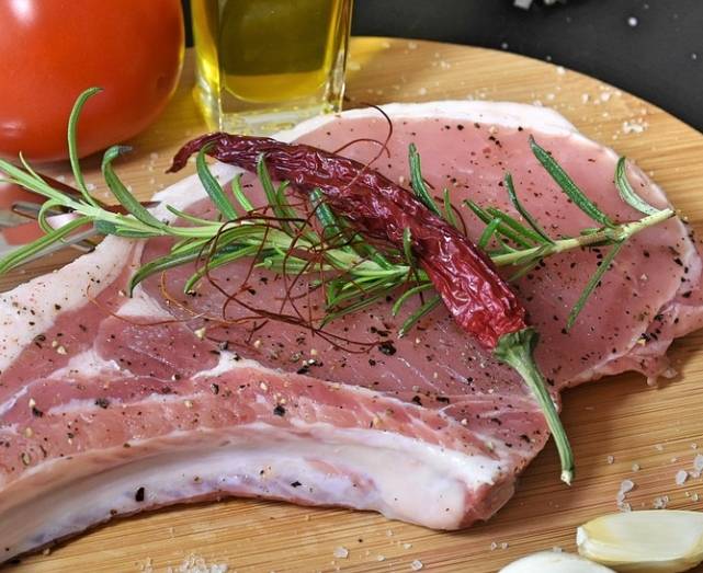 생 돼지고기 위에 마른 고추가 놓여있다.