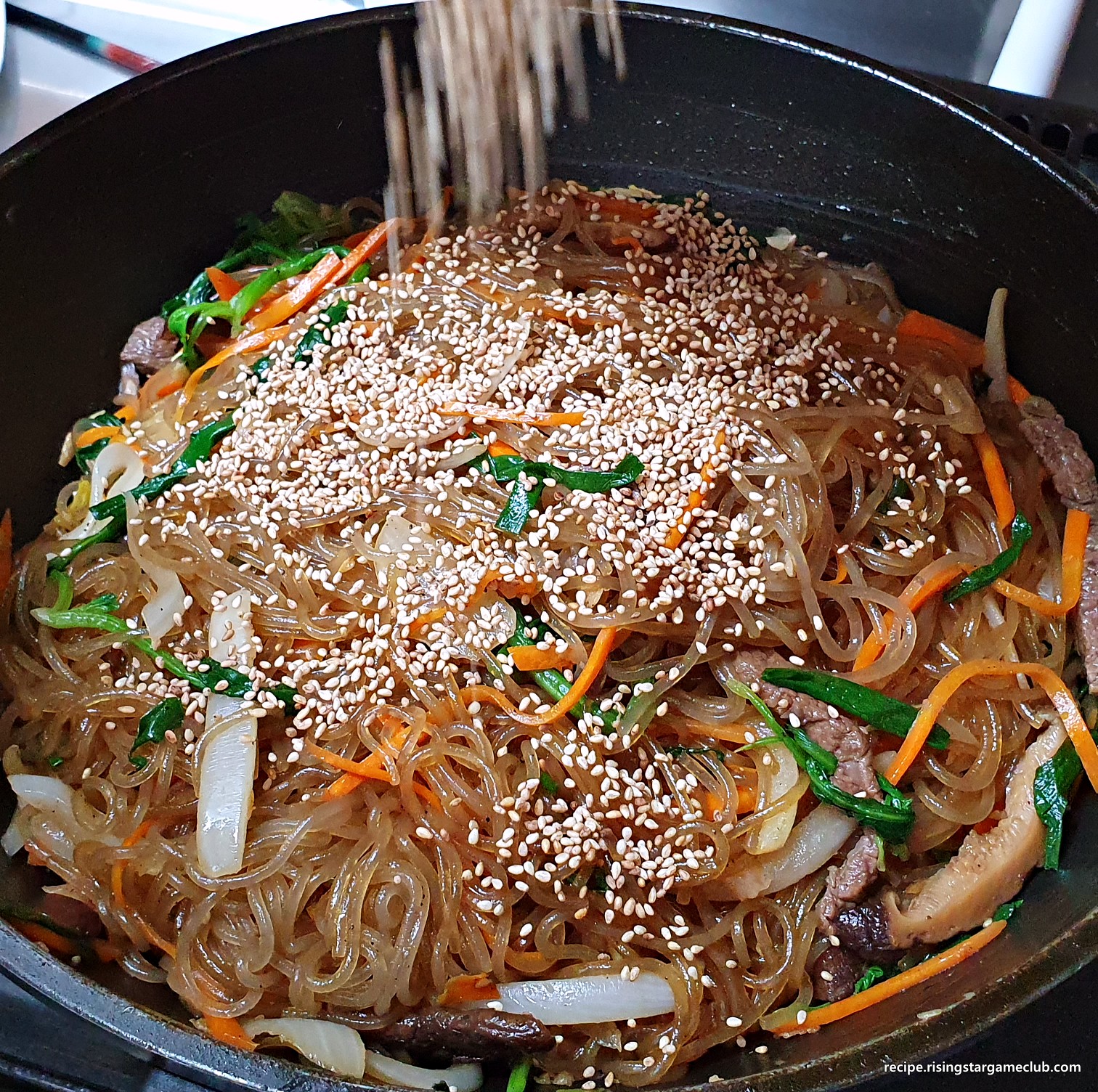 완성된 잡채 위에 통깨를 뿌려주는 사진