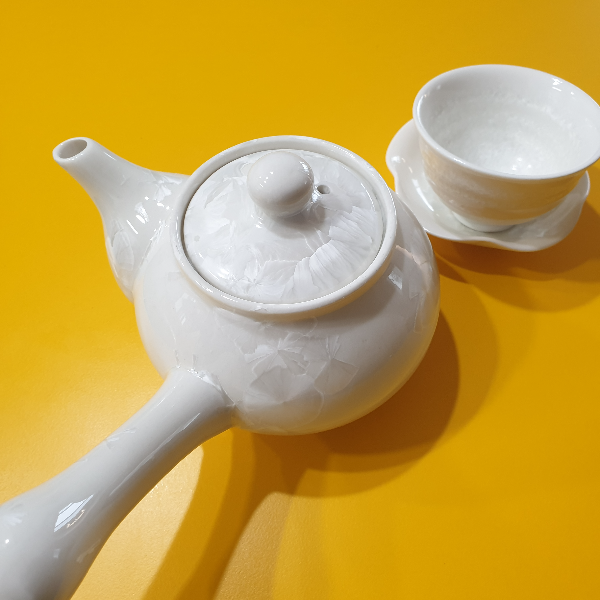 노란색 테이블 위에 다완과 찻잔이 있다. 다완과 찻잔은 크림색이다.