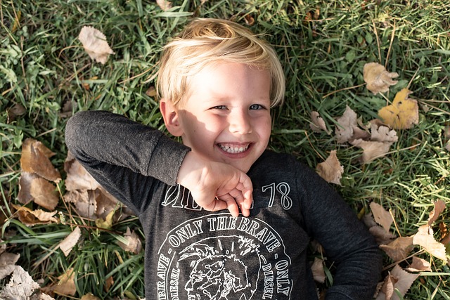 잔디밭에 누워 웃고 있는 소년의 사진