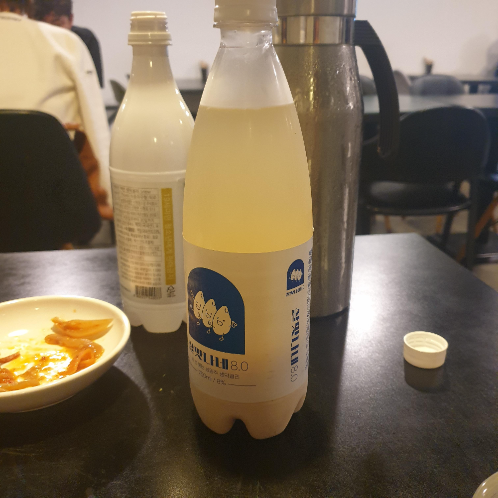 테이블 위에 막걸리 병 두 개와 물병이 놓여있다.