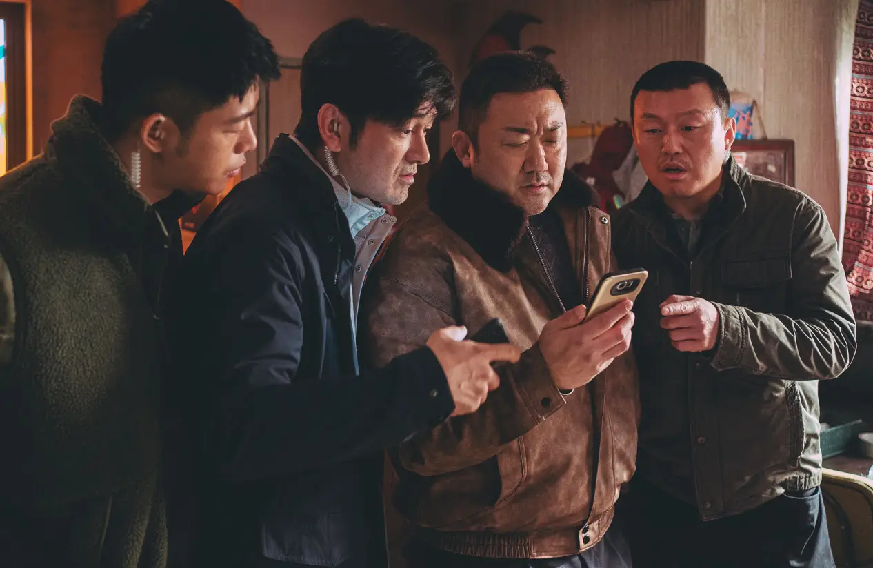 범죄도시-형사들 4명이 모여서 마동석이 들고 있는 핸드폰을 함께 보는 모습
