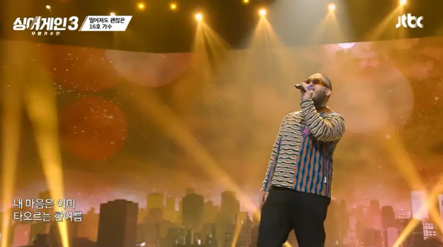 싱어게인3-
황금빛 배경 노랑과 파랑 줄무늬 긴팔티에 검은색바지를 입고 검은선글라스에 왼손 마이크를 들고 노래하는 16호