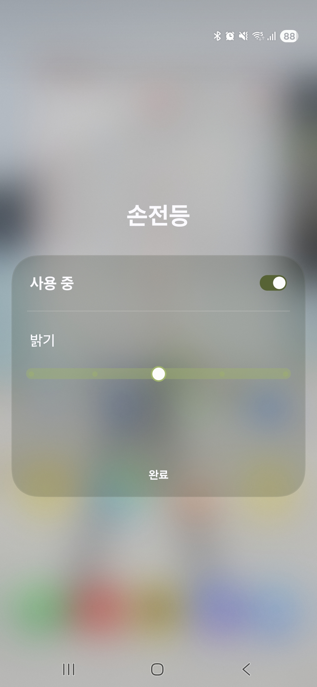 스마트폰 상단바를 아래로 두 번 내려 빠른 설정창 목록에서 손전등 아이콘의 글자 부분을 터치해 밝기 조절 단계를 확인하는 장면