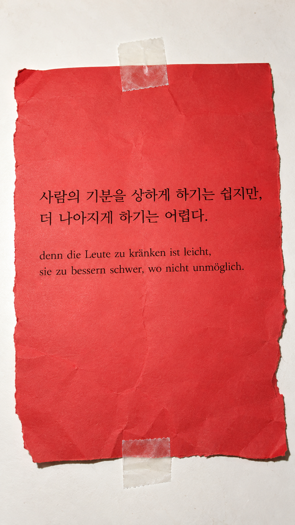 쇼펜하우어 명언 23 사람의 기분을 상하게 하기는 쉽지만, 더 나아지게 하기는 어렵다. 투명 테이프로 수선한 붉은 종이 배경의 한글&middot;독일어 이미지