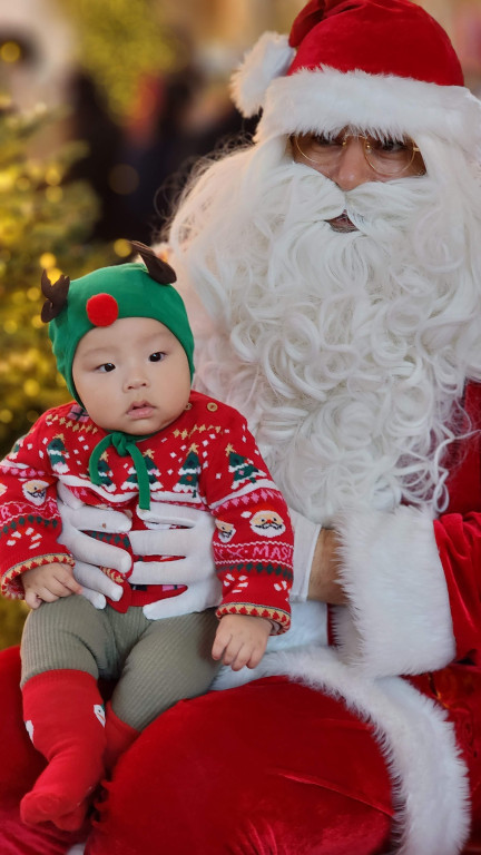 파라다이스 시티 산타 썰매 포토존에서 산타와 함께 촬영 중인 아기 사진. 크리스마스 조명과 트리가 배경으로 연말 분위기를 담은 사진