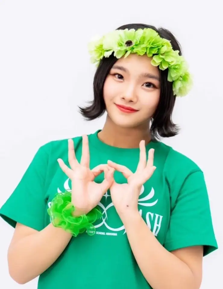 한일-흰색 벽앞 초록색 반팔티 초록색 나뭇잎 왕관을 쓰고 서있는 스미다 아이코