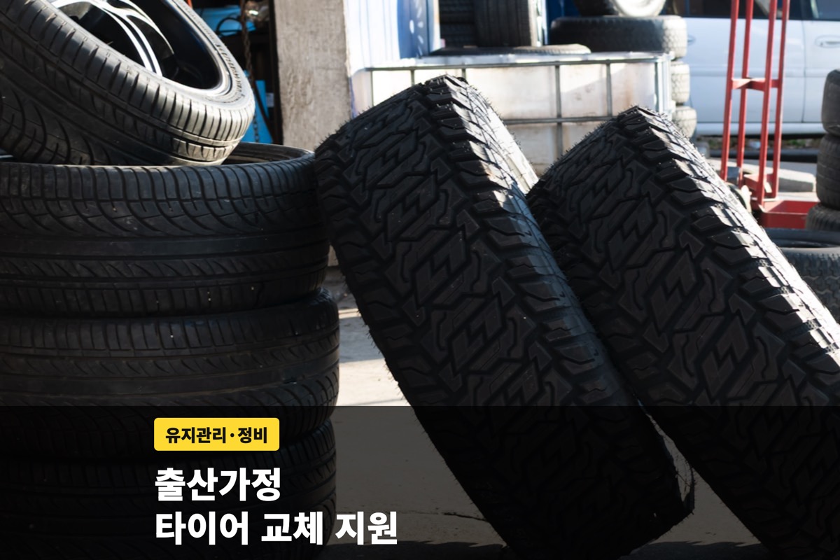 정비소 앞에 쌓아 둔 자동차 타이어와 출산가정 지원 안내 문구