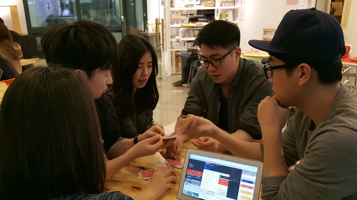 숙련된 회원의 카드 마술 시연을 지켜보는 모습