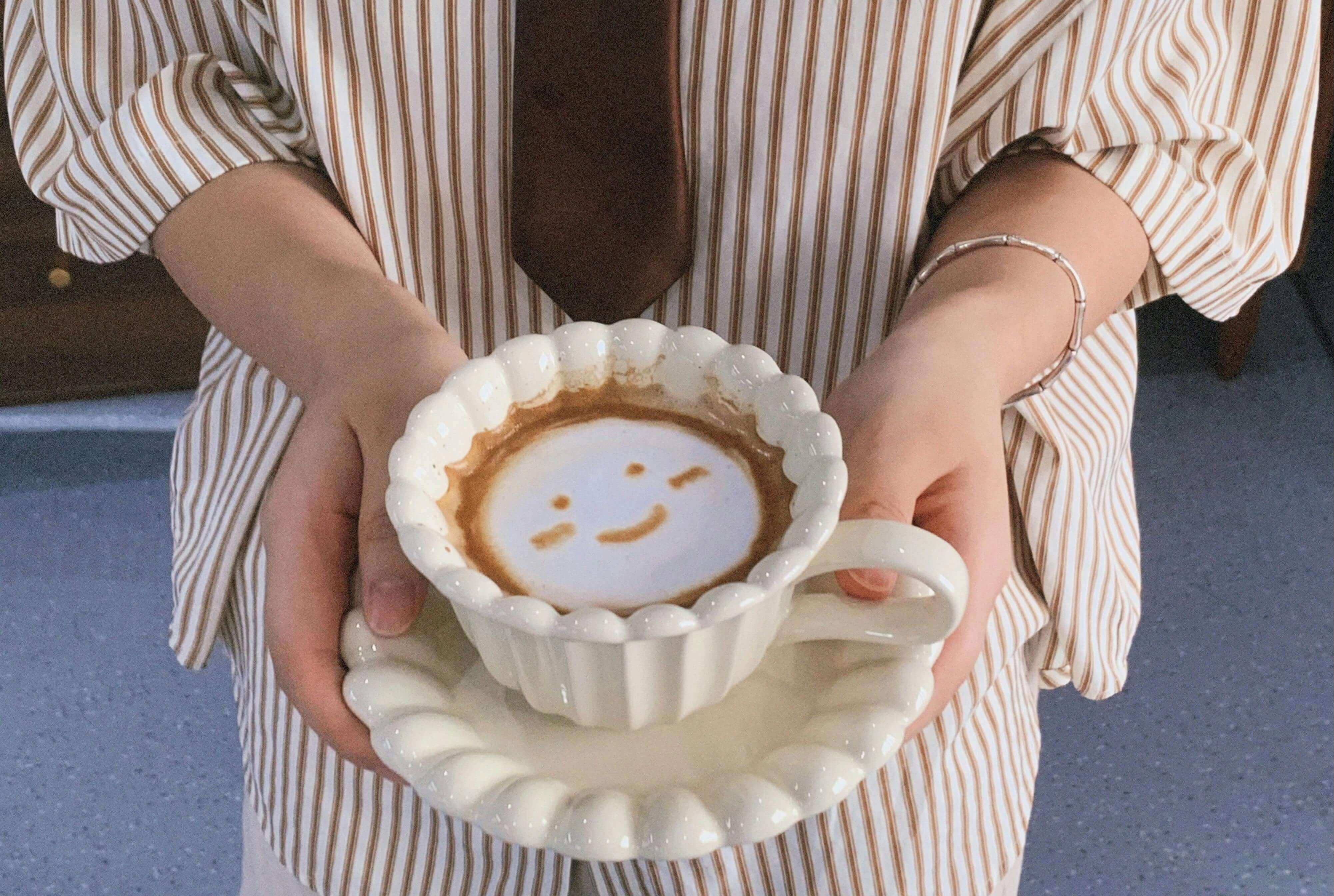 하얀 머그잔에 담긴 라떼 위에 웃는 얼굴이 그려진 라떼 아트, 따뜻한 감성 전달