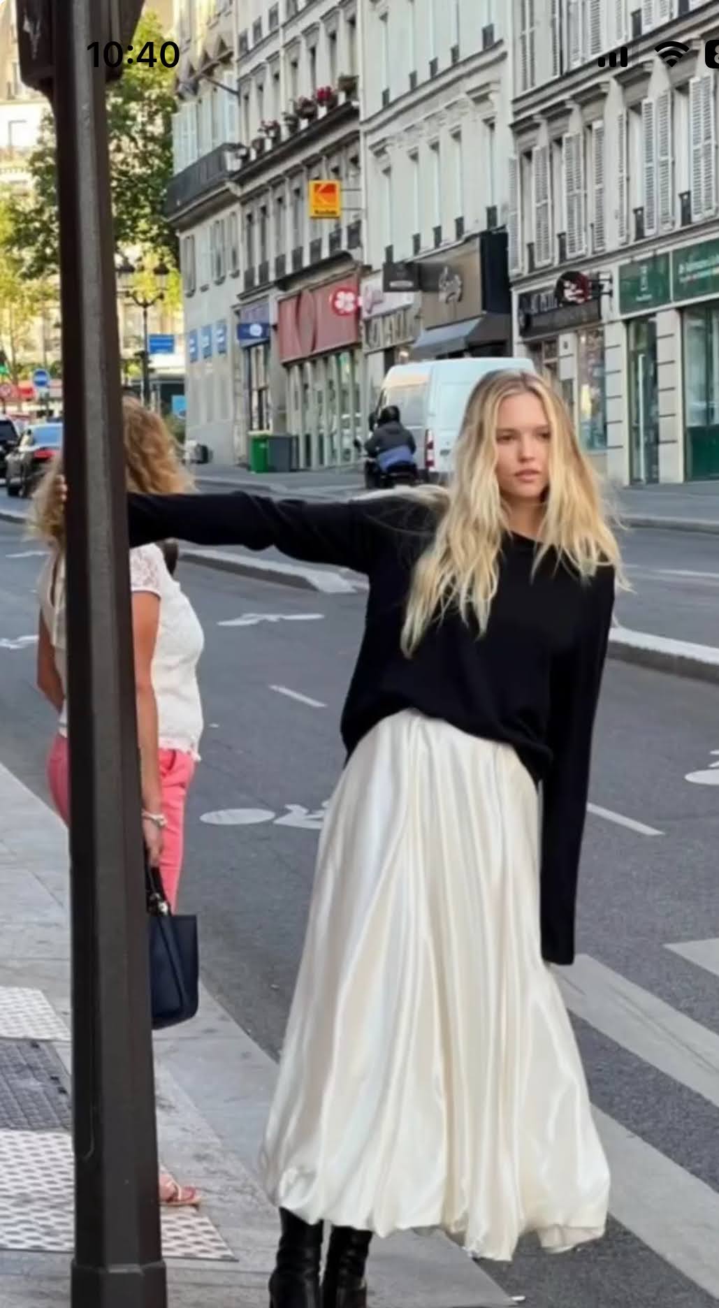 번화가 속 화이트 스커트와 검은색 스웨터를 입은 여인