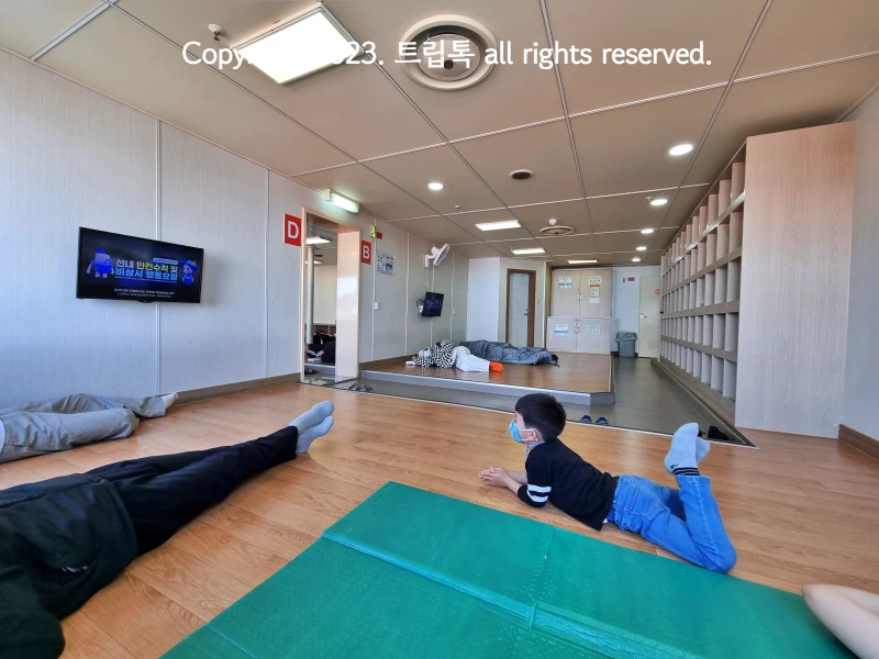 배가 운항을 시작하면서 안전수칙이 나오는 티비를 보는 아이의 모습