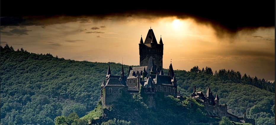 언덕 위에 오래된 성이 있고, 하늘은 곧 폭풍이 몰아칠 것 같은 모습을 하고 있는 사진