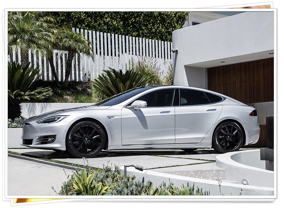 은색 테슬라 모델 S가 현대적인 건축물 앞에 주차된 측면 사진