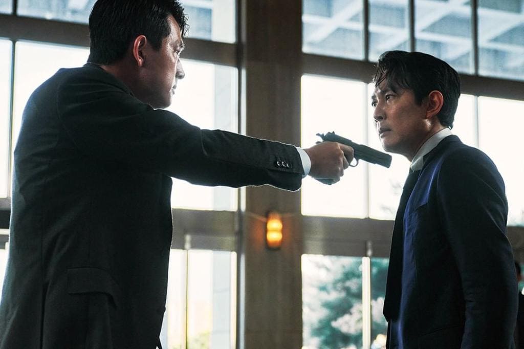 한 남성이 다른 남성에게 총을 겨누고 노려보는 장면