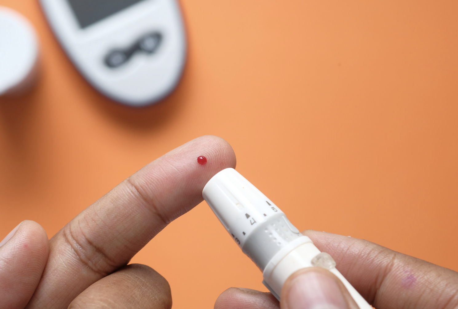 person checking their glucose by glucometer poking finger