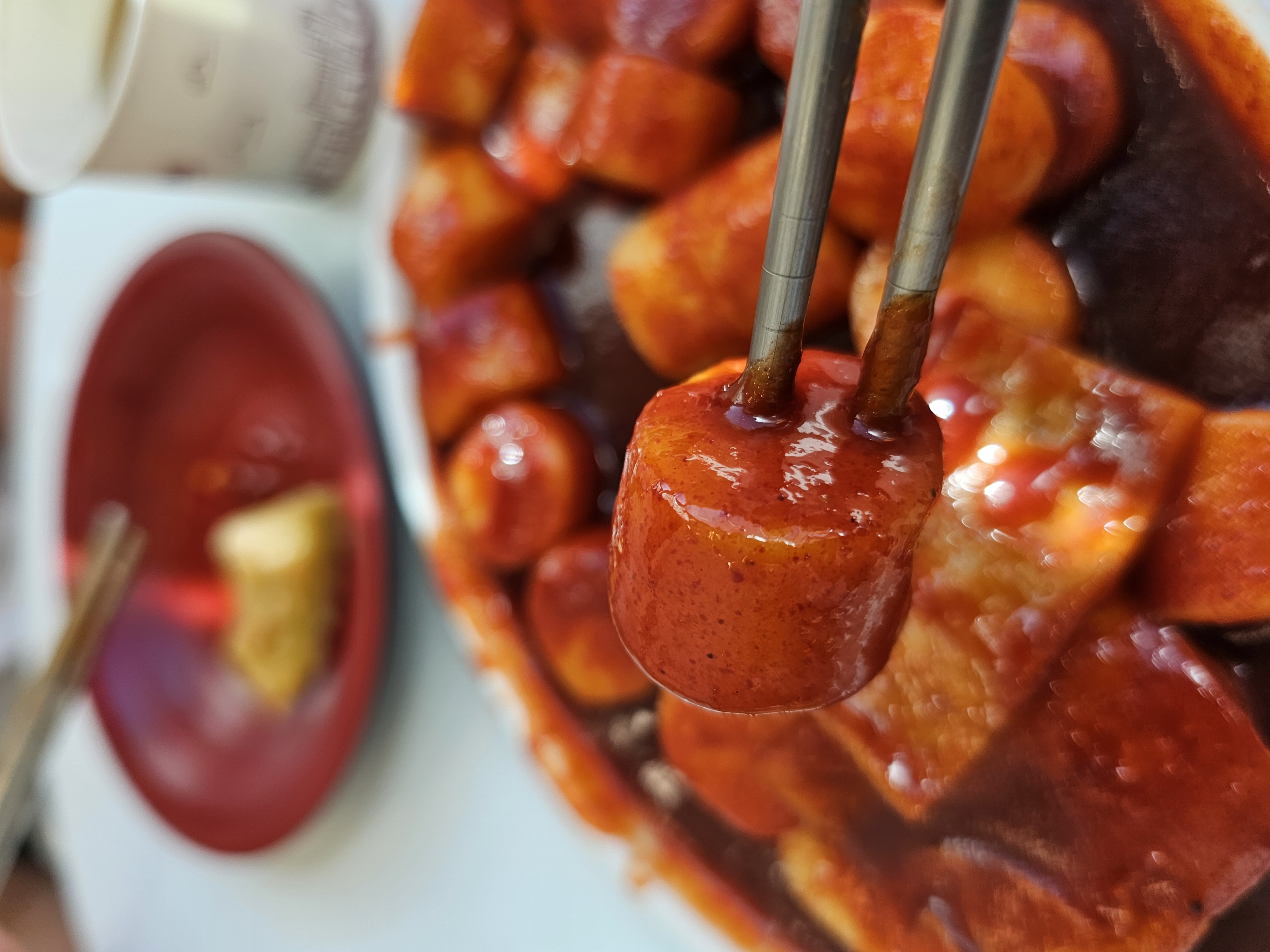 대왕 판 떡볶이의 꾸덕한 양념이 가득 묻은 쌀떡을 젓가락을 들은 모습