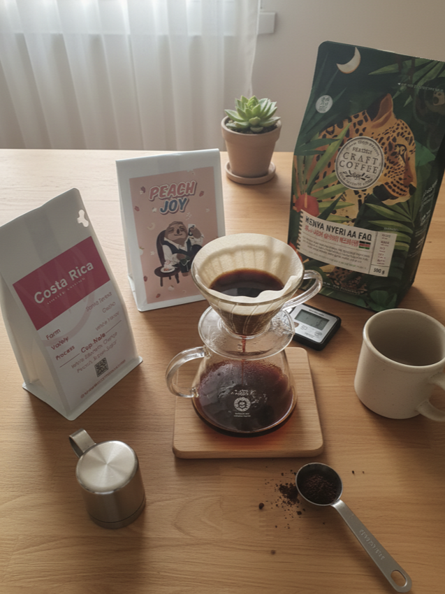 테이블 위에 3개의 원두와 서버와 드리퍼가 올려져 있다.