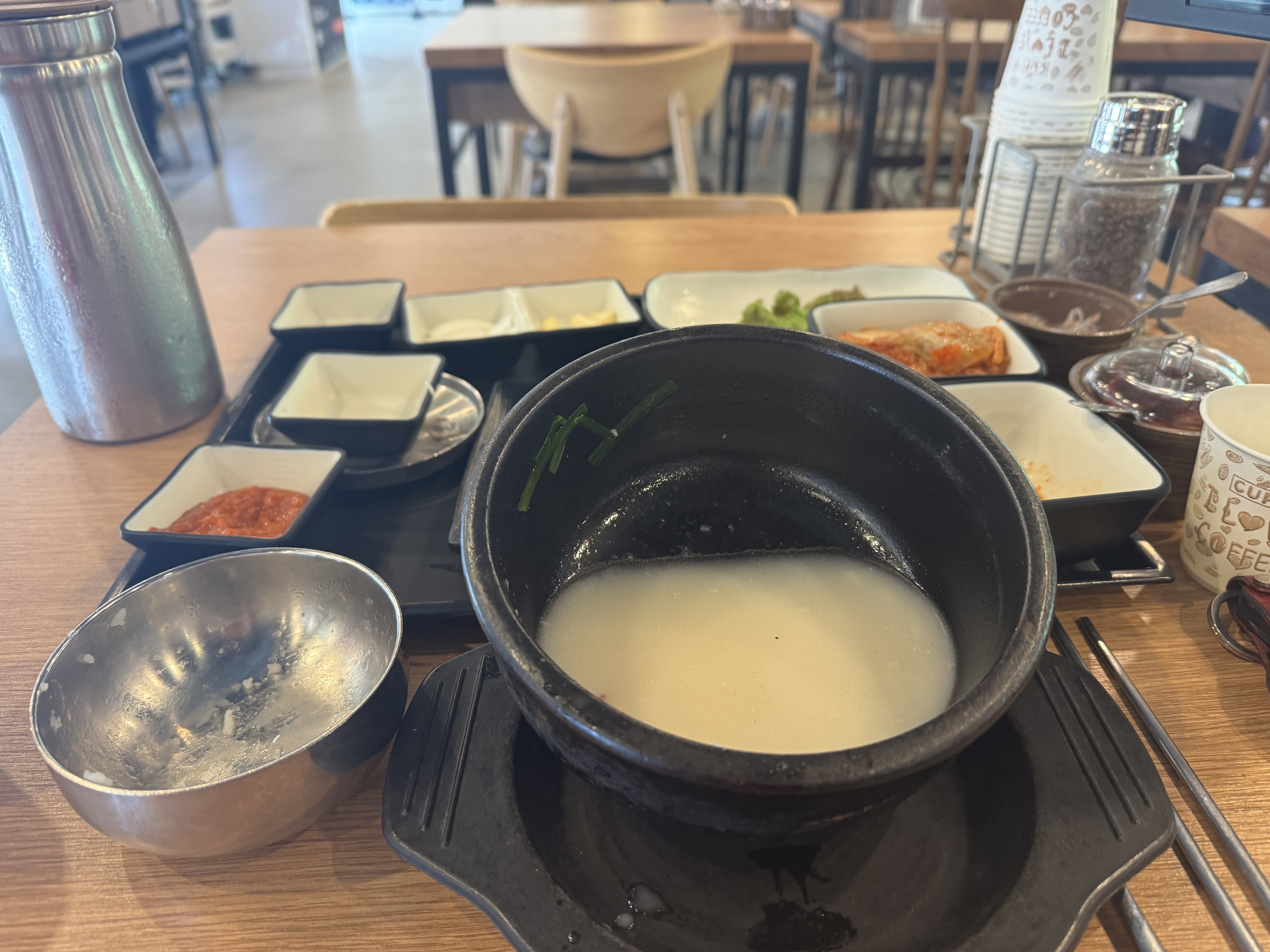 경자국밥 용인본점에서 국밥을 모두 먹고 난 뒤, 국물만 조금 남은 빈 뚝배기와 밥그릇. 테이블 위에는 김치, 깍두기, 쌈채소, 수육 접시, 소면 등 밑반찬 그릇들이 비워진 채 놓여 있다.