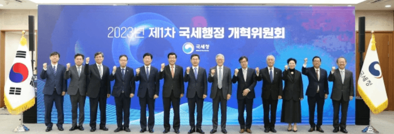 2023년-제1차-국세행정개혁위원회에-참여한-13명이-단체사진을-찍고있는-장면