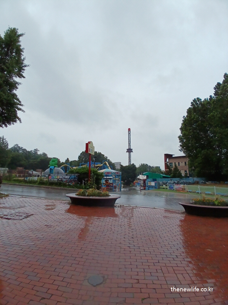Distant view of Children&rsquo;s Grand Park&rsquo;s water play area and amusement rides on a rainy day./비 오는 날 멀리서 바라본 서울 어린이대공원의 수영장과 놀이기구 구역.