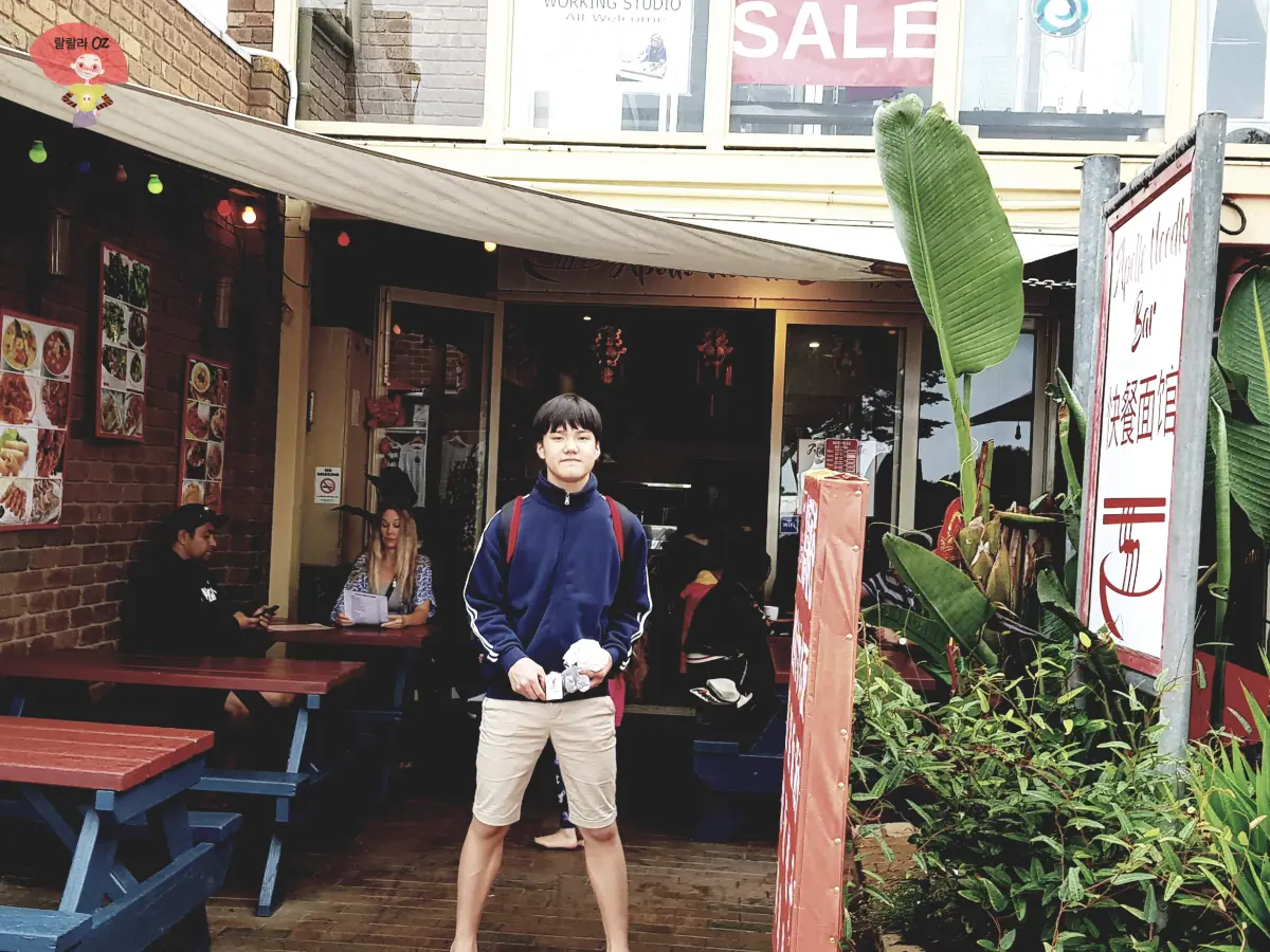 호주-멜번-그레이트-오션-로드-아폴로-베이-몰-아폴로-누들-바-아시아요리-음식점-앞에서-작은-인형을-들고-포즈를-취하고-있는-소년