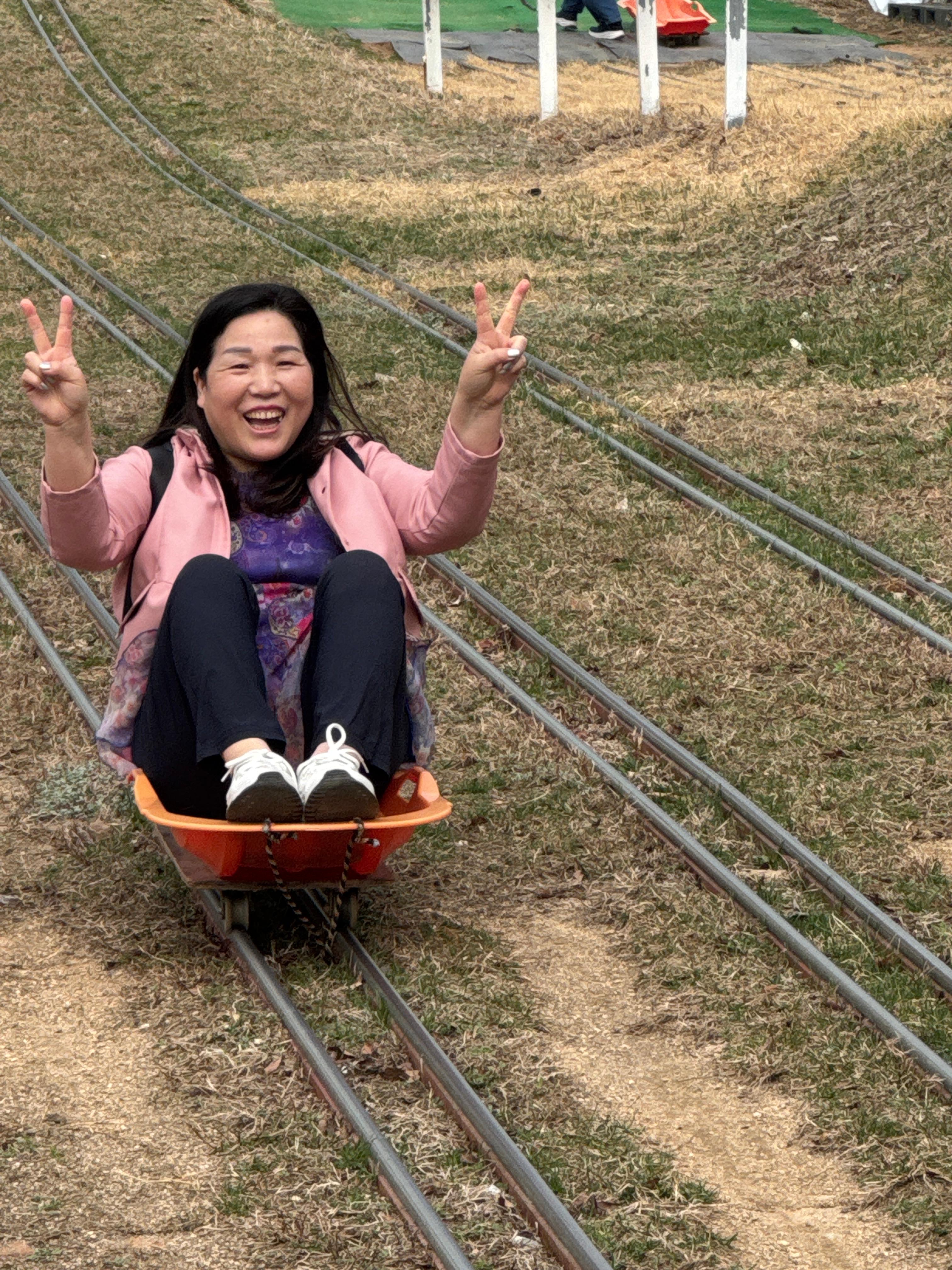 레일썰매를 탄 선생님이 웃으며 브이를 하고있는 모습