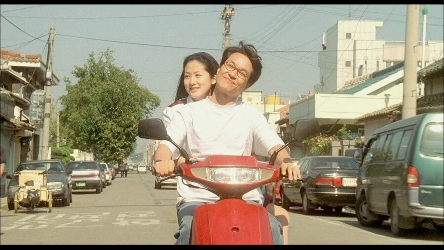 8월의크리스마스영화의한장면남녀주인공이오토바이를타고시내를돌아다니고있다.행복한표정.