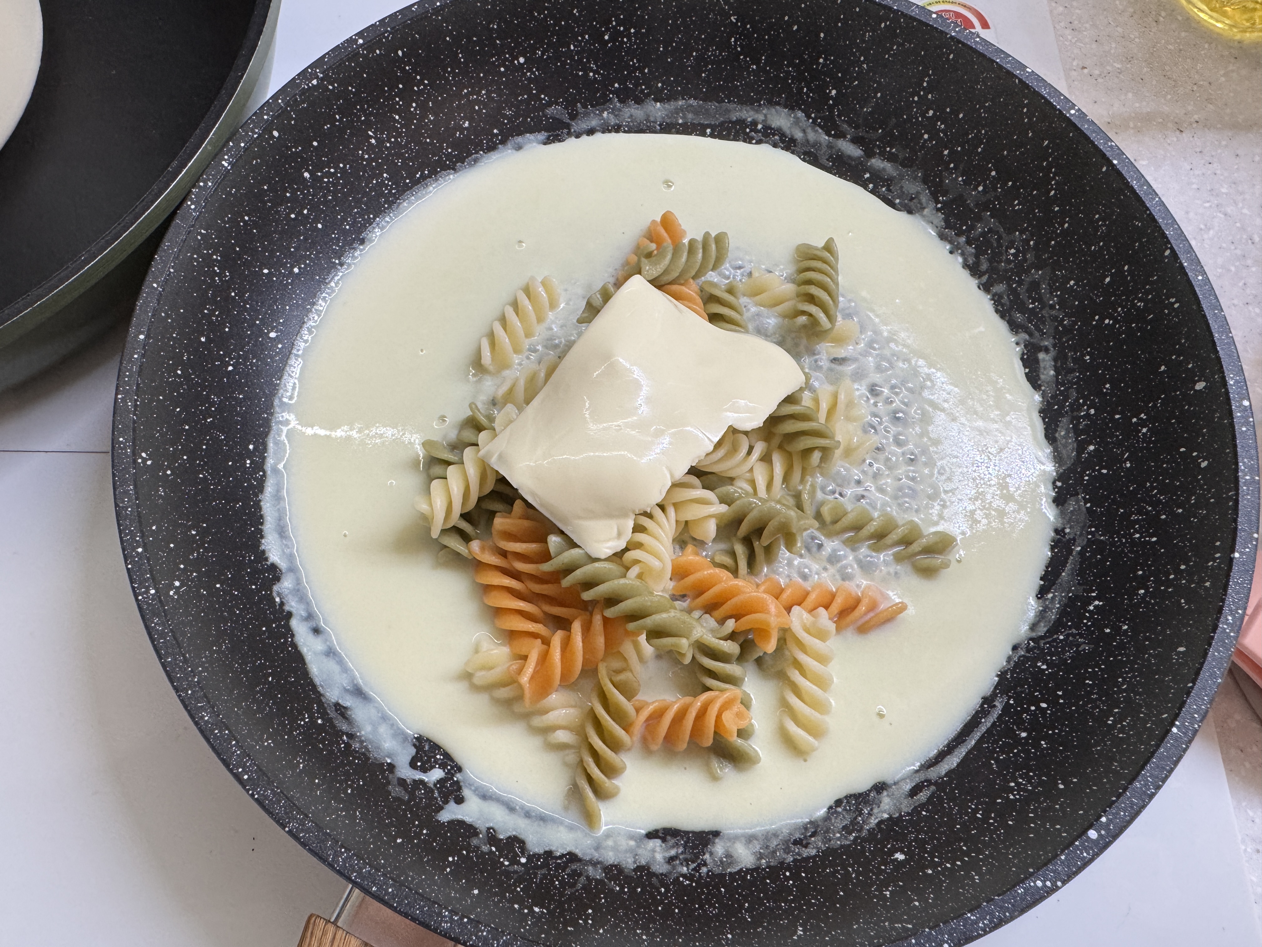 팬에 분유 혼합물, 삶은 푸실리, 치즈 반 장을 넣고 졸이는 중