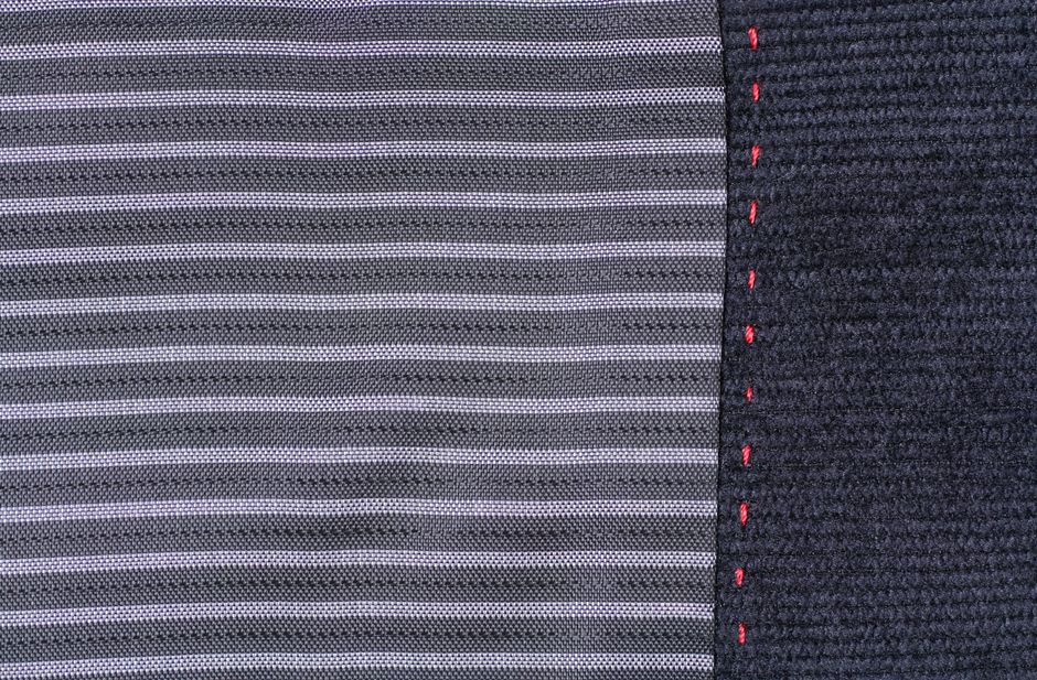 Detailed close-up of striped fabric featuring contrasting red stitching along the edge, highlighting texture.